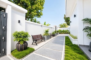 A modern outdoor pathway leading to a building with a bench and potted plants. - Opal Oasis (Gadhdhoo)