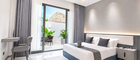 Una habitación de hotel moderna con una cama, mesitas de noche, un escritorio y un balcón con plantas.