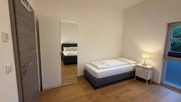 A bedroom with a bed, bedside table, and a mirror.