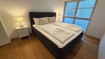 Ein Schlafzimmer mit einem Bett, Nachttischen und einem Fenster.