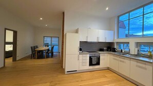 Eine moderne Küche mit weißen Schränken, einem eingebauten Backofen und einem großen Fenster.
