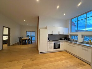 A modern kitchen with white cabinets, a built-in oven, and a large window.