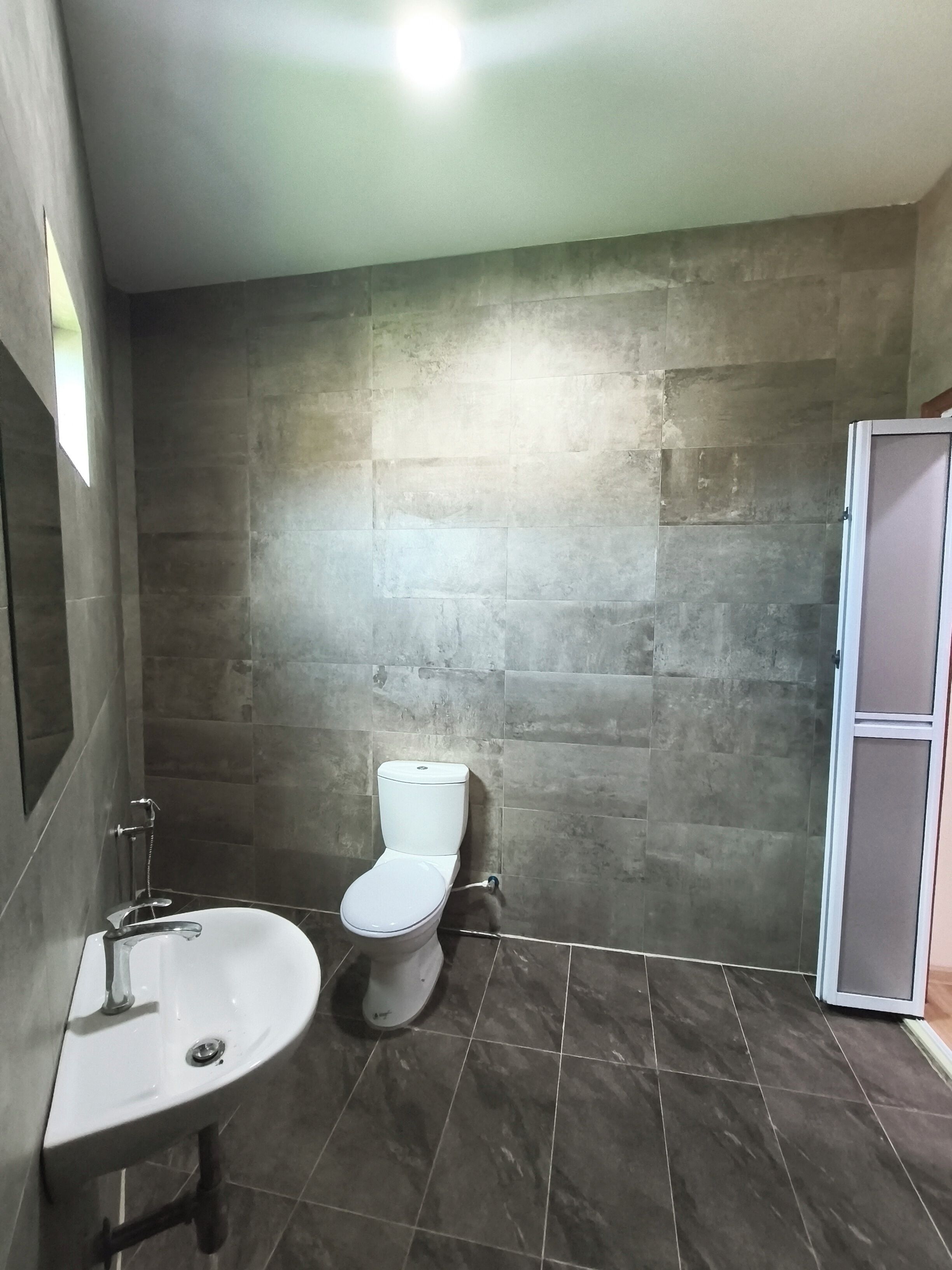 Un baño con inodoro, lavamanos y zona de ducha.