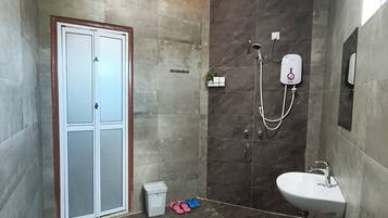 A bathroom with a toilet, a sink, a shower, and a door.