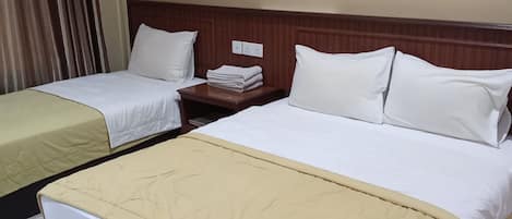 A hotel room with two beds, a wooden headboard, and a nightstand with a lamp.