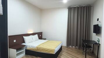 Habitació d'hotel amb llit, taula de nit, escriptori i televisió.