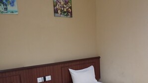 A hotel room with two single beds, a wooden nightstand, a small drawer, and two wall-mounted paintings. - Tanjong Inn by StayZy (Kota Bharu)