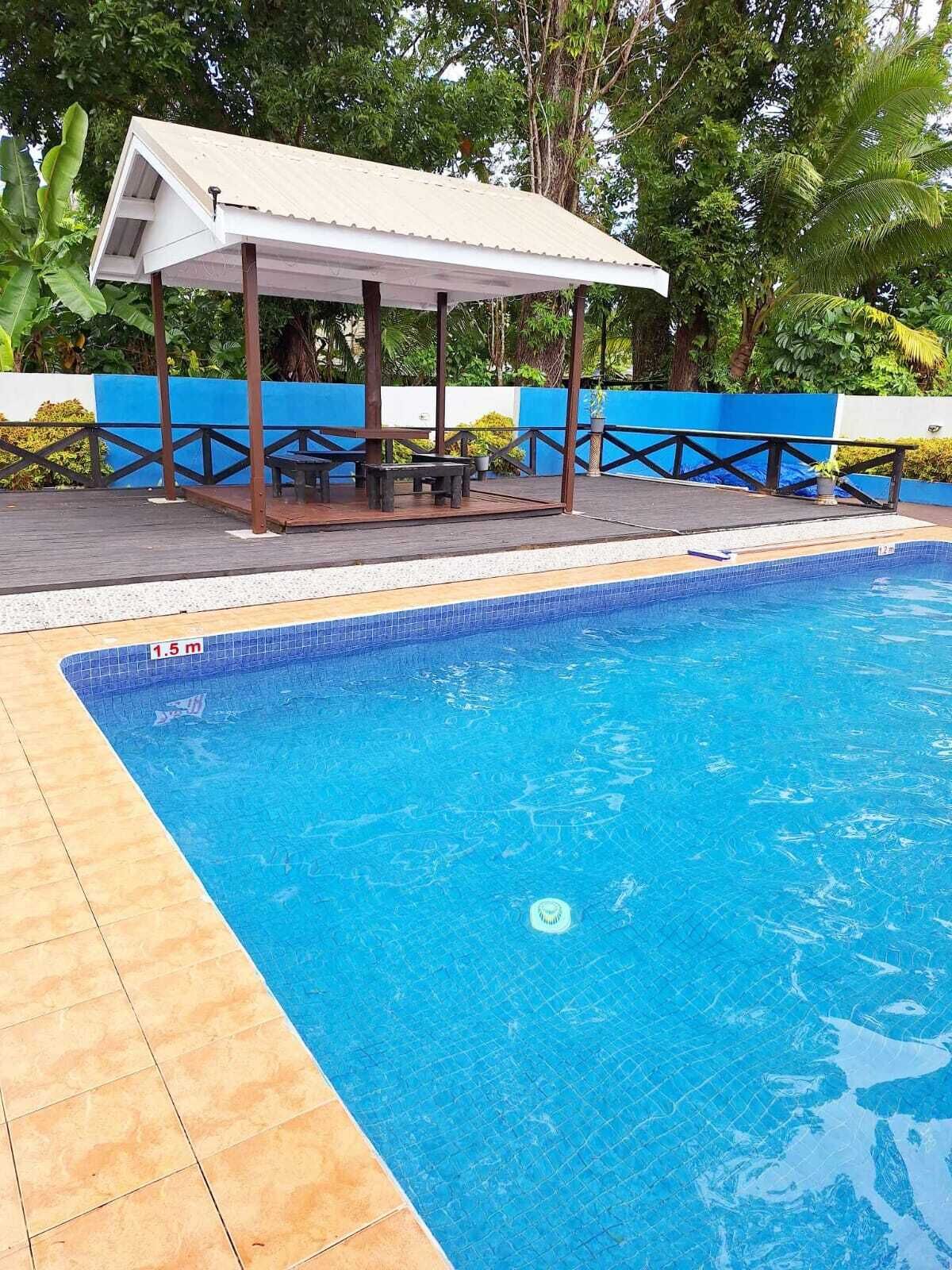 Une piscine dotée d’un espace de repos couvert et d’un panneau de sécurité indiquant une profondeur de 1,5 mètre.