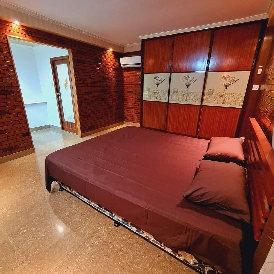 Un dormitorio con una cama grande, un armario de madera y una puerta que da a otra habitación.