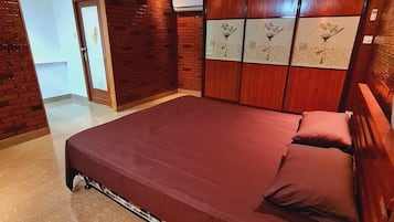 Un dormitorio con una cama grande, un armario de madera y una puerta que da a otra habitación.