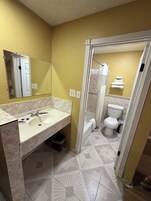 Un baño con lavamanos doble, espejo, ducha e inodoro.