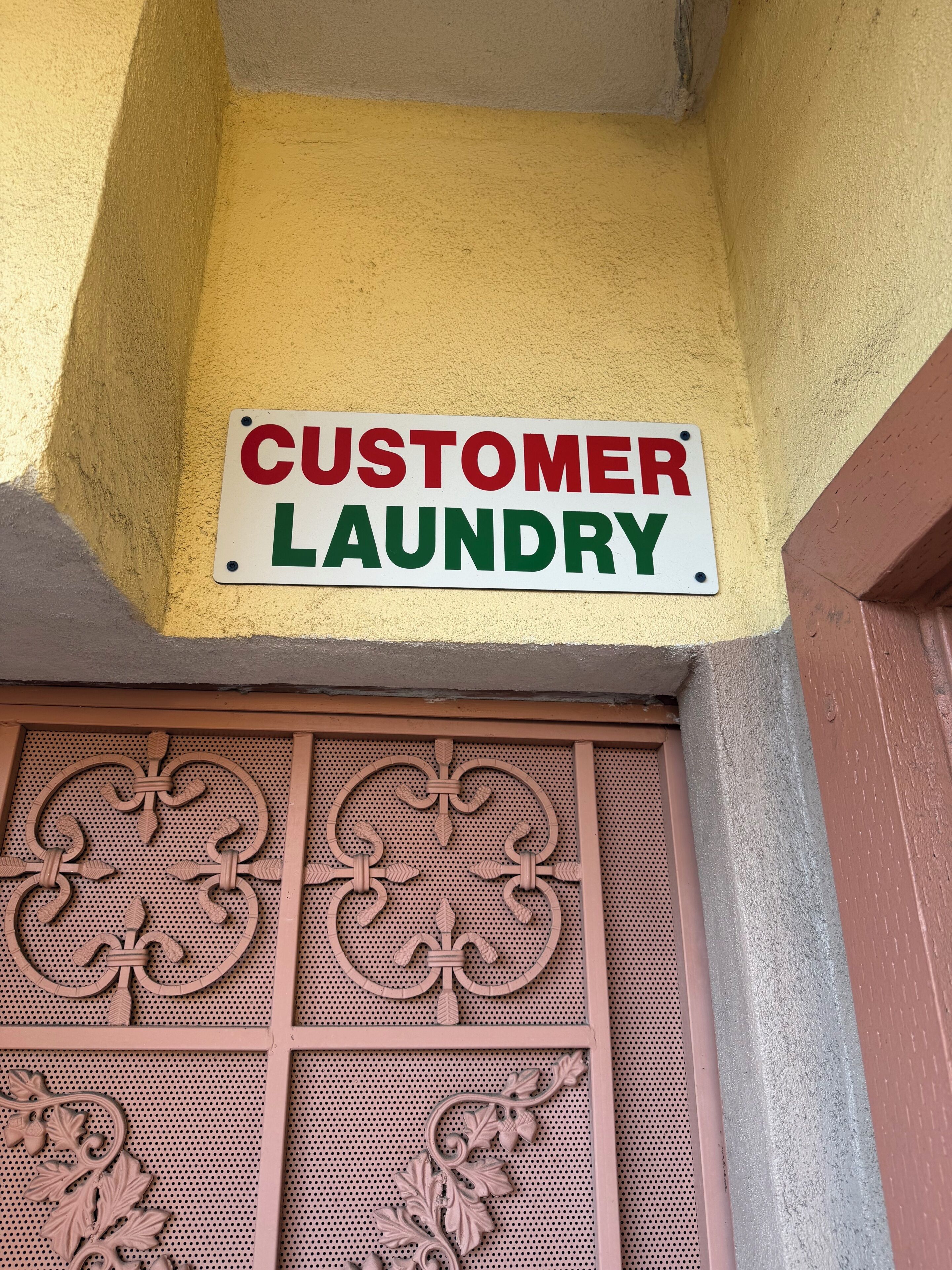 Letrero que dice 'CUSTOMER LAUNDRY' colgado en un edificio.