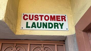 Letrero que dice 'CUSTOMER LAUNDRY' colgado en un edificio.