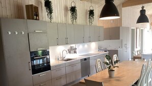 A modern kitchen with white cabinetry, a central island, and pendant lighting. - 4 Star Holiday Home in Vaeggerlose (Vaeggerlose)