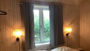 A room with a bed, two wall-mounted lamps, a window with curtains, and a bench. - 4 Star Holiday Home in Vaeggerlose (Vaeggerlose)