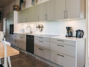 A modern kitchen with stainless steel appliances, a dishwasher, and a coffee maker. - 4 Star Holiday Home in Vaeggerlose (Vaeggerlose)