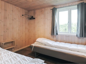 A room with wooden walls, a window with curtains, and two beds. - 4 Star Holiday Home in Vaeggerlose (Vaeggerlose)