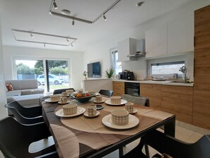 Uma cozinha moderna com área de refeições, um sofá e vista para o exterior.