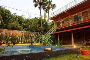 A swimming pool with a glass wall, a staircase, and a building with balconies.
