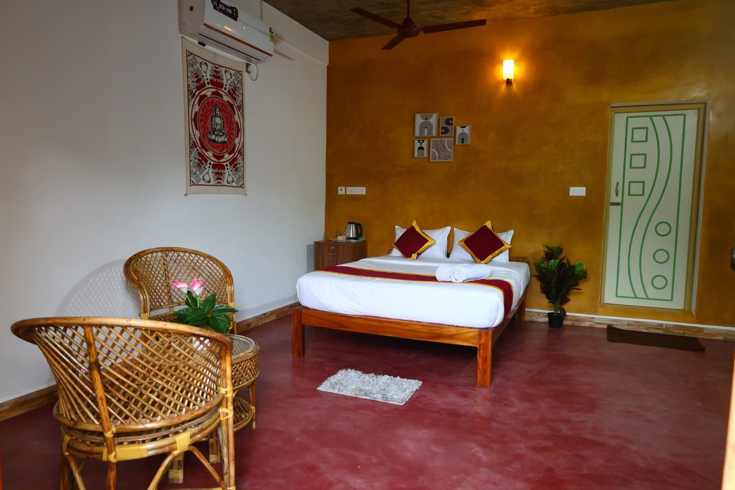 A hotel room with a bed, a chair, a small table, and a wall with artwork.