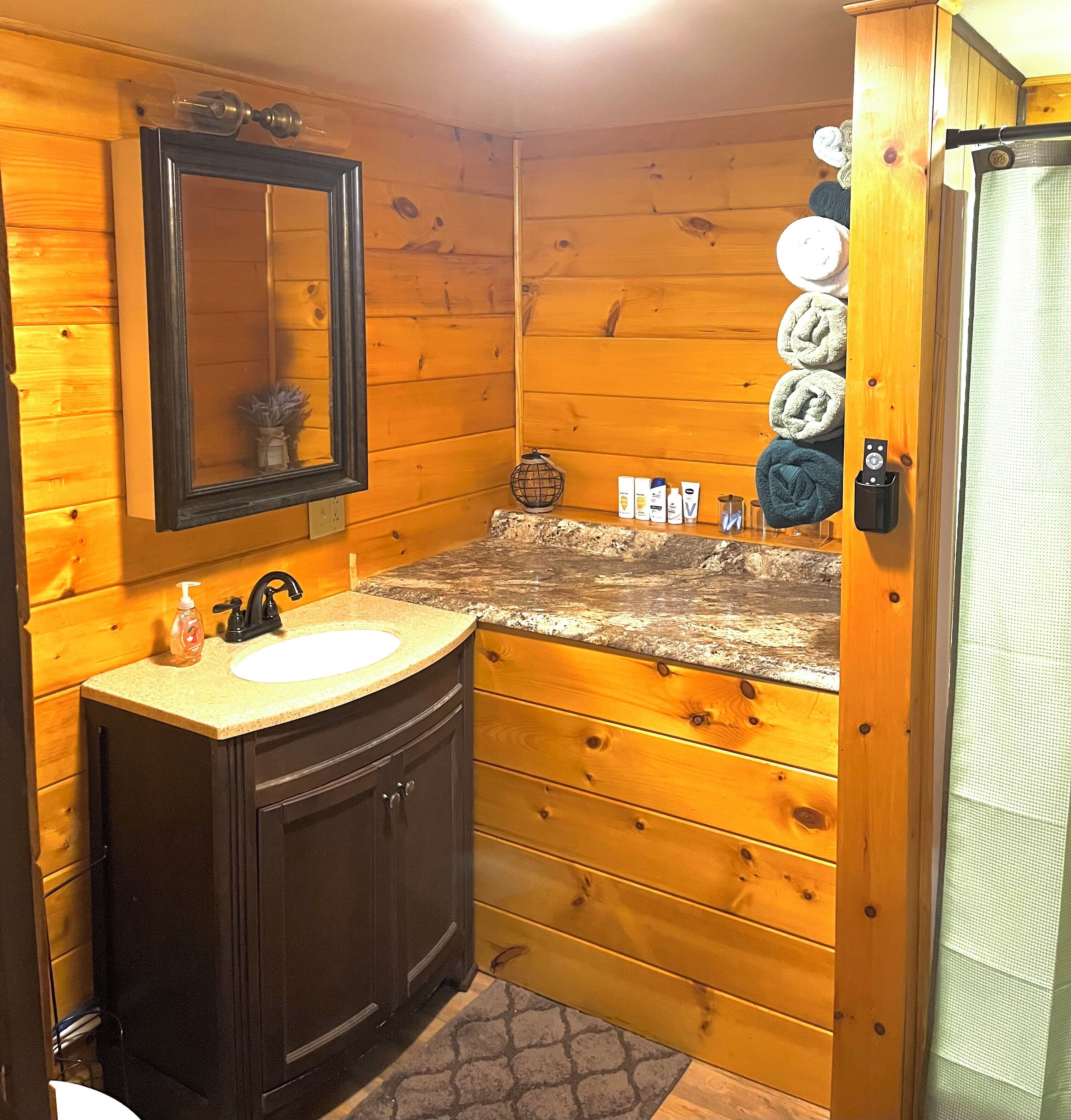 Casa de banho de uma cabana de madeira, com lavatório, espelho e produtos de higiene.
