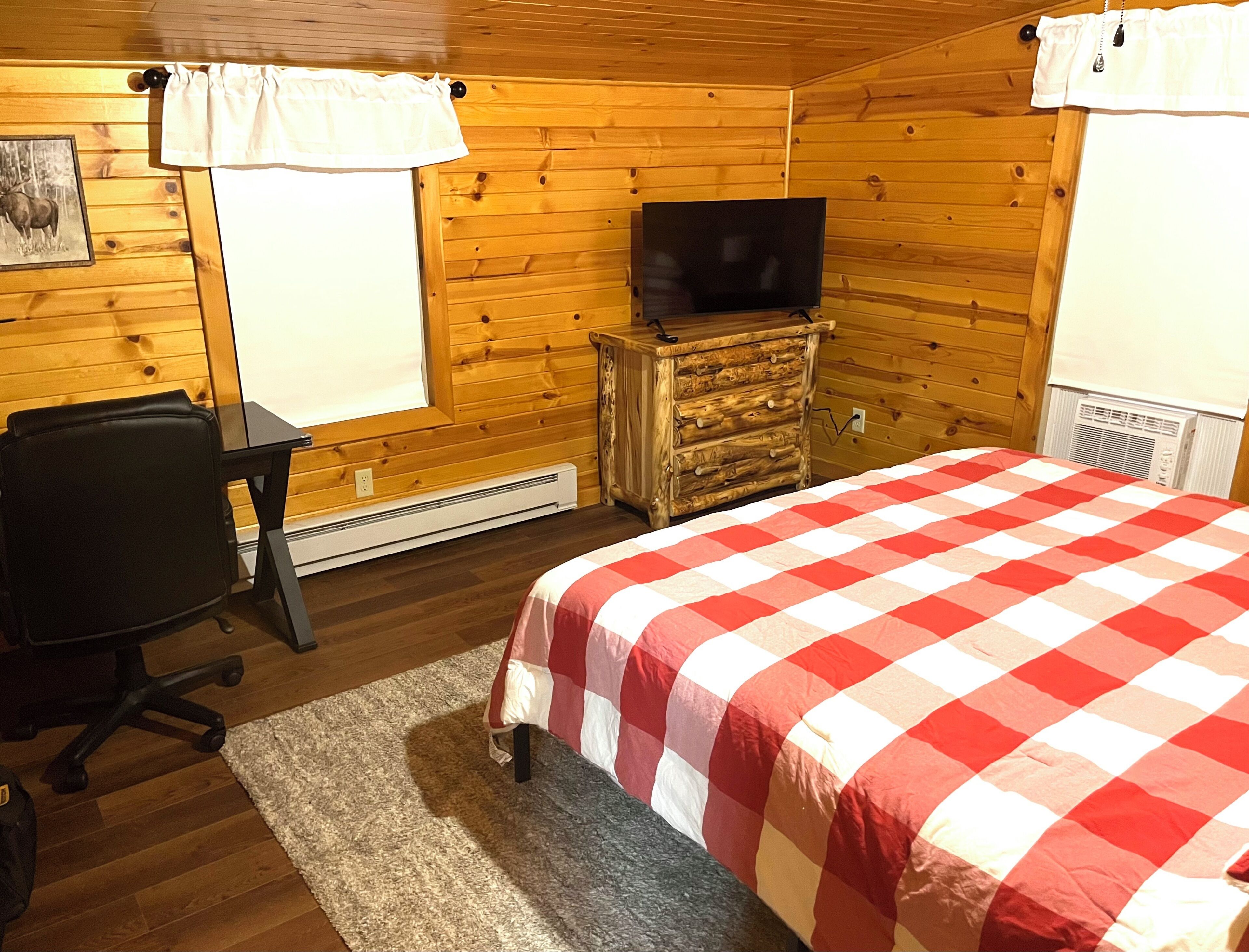 A room with a bed, a desk, a chair, a dresser, a television, and a window.