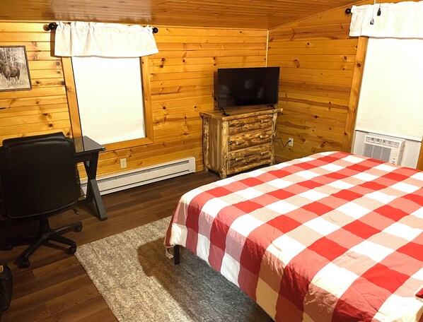 A room with a bed, a desk, a chair, a dresser, a television, and a window.