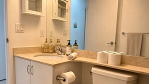 Een badkamer met wastafel, spiegel, toilet en een prullenbak.