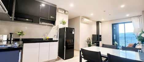 Una cocina moderna con armarios negros, un refrigerador y un comedor con mesa y sillas.