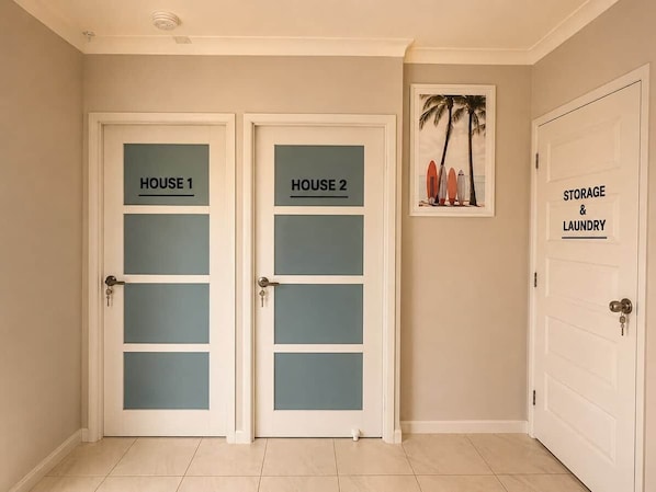 A hallway with two doors labeled 'HOUSE 1' and 'HOUSE 2' and a door labeled 'STORAGE & LAUNDRY'.