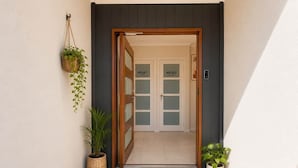 A modern entrance with a welcome mat, two doors labeled 'HOUSE 1' and 'HOUSE 2', and potted plants. - Private Duplex - Pimpama / Gold Coast (Pimpama)