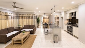 A modern living room with a sofa, coffee table, and a dining area with chairs. - Private Duplex - Pimpama / Gold Coast (Pimpama)