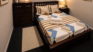 A bedroom with a bed, dresser, ceiling fan, wall decor, and a bedside lamp. - Private Duplex - Pimpama / Gold Coast (Pimpama)