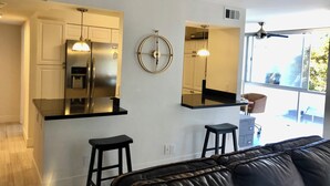 Una cocina moderna con un refrigerador de acero inoxidable, una encimera negra y un taburete de bar.
