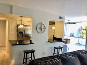 A modern kitchen with a stainless steel refrigerator, a black countertop, and a bar stool. - CORONADO SHORES 
Las Flores Tower. Beautiful 2 bed/2 bath
Short-Term & Long-Term (Coronado)