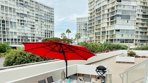 Terraza en la azotea con una mesa lista para comer, rodeada de edificios modernos.