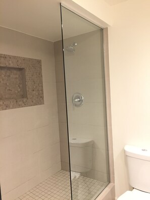 A glass-enclosed shower area with a tiled floor, a toilet, and a wall with a decorative tile pattern. - CORONADO SHORES 
Las Flores Tower. Beautiful 2 bed/2 bath
Short-Term & Long-Term (Coronado)