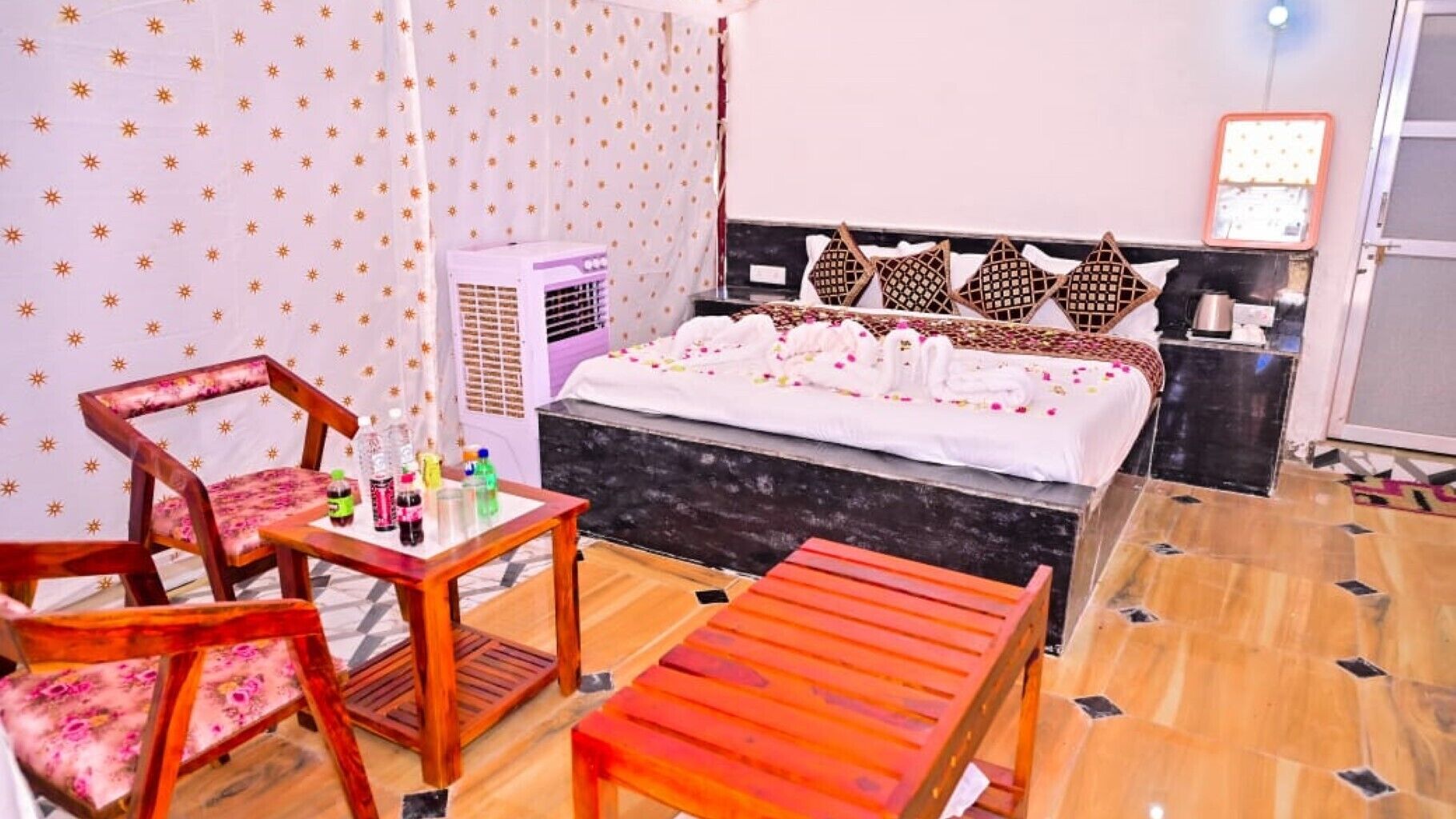 A hotel room with a bed, a desk, two chairs, a small table, and a bench.