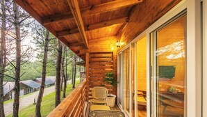 A wooden balcony with a view of trees and a building in the background. - Leikyard Resort Shillong (Shillong)
