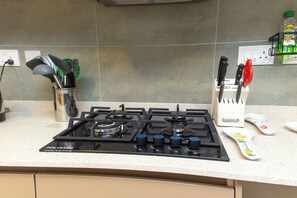 A kitchen with a gas stove, a utensil holder, and a knife block. - Peaceful 2-bedroom apartment with AC in vibrant Lekki (Lekki)