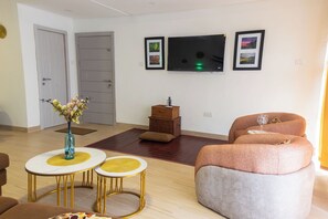 A modern living room with a flat-screen TV, a sofa, a coffee table, and a decorative vase. - Peaceful 2-bedroom apartment with AC in vibrant Lekki (Lekki)