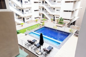 A rooftop swimming pool with a view of a multi-story building. - Peaceful 2-bedroom apartment with AC in vibrant Lekki (Lekki)