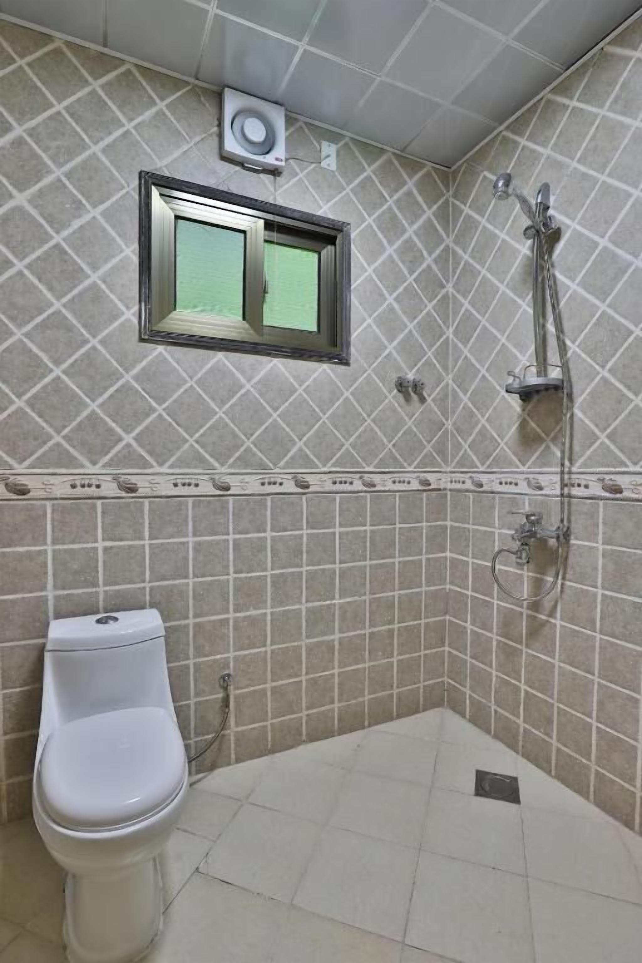 A bathroom with a toilet, a shower, and a window.