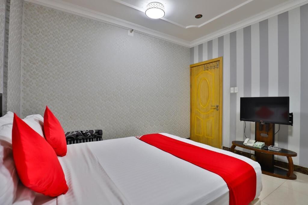 A hotel room with a bed, a television, and a door.