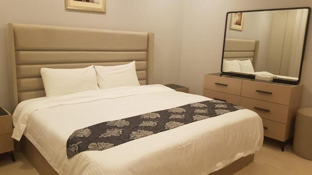 Ein Hotelzimmer mit Bett, Schminktisch, Nachttisch und Spiegel.
