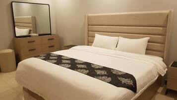 A hotel room with a bed, a dresser, a mirror, and a nightstand.