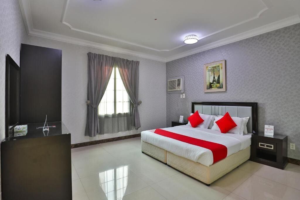 Habitación de hotel con una cama grande, un escritorio, un televisor de pantalla plana y una ventana con cortinas.