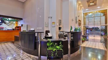 A hotel reception area with a reception desk, a clock, and a map on the wall.