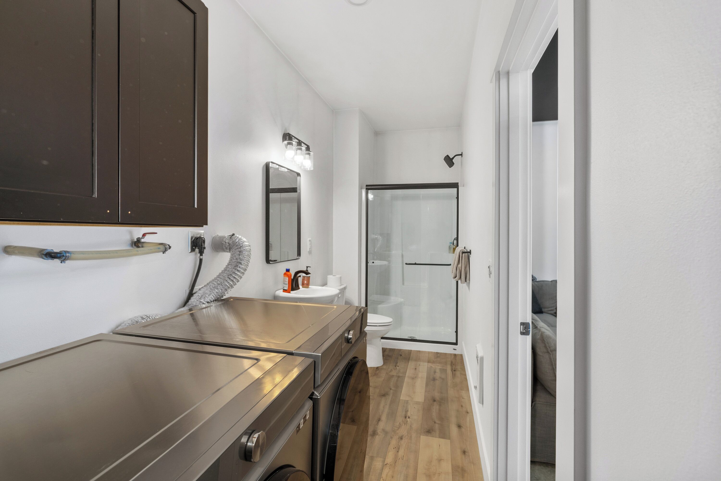A modern bathroom with a stainless steel vanity, a glass shower enclosure, and a white sink.