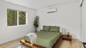 Et moderne soveværelse med en seng, et vindue og en aircondition.